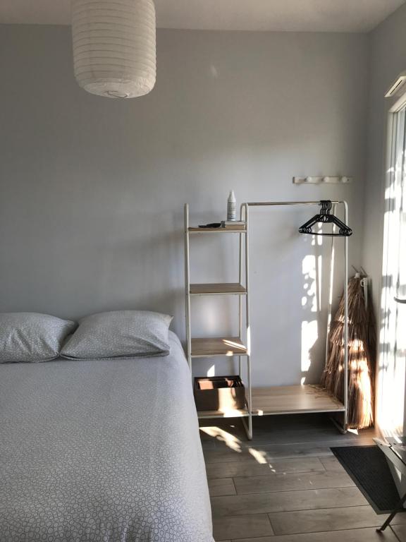 um quarto com uma cama e uma prateleira ao lado de uma janela em les aulnes de sanguinet em Sanguinet
