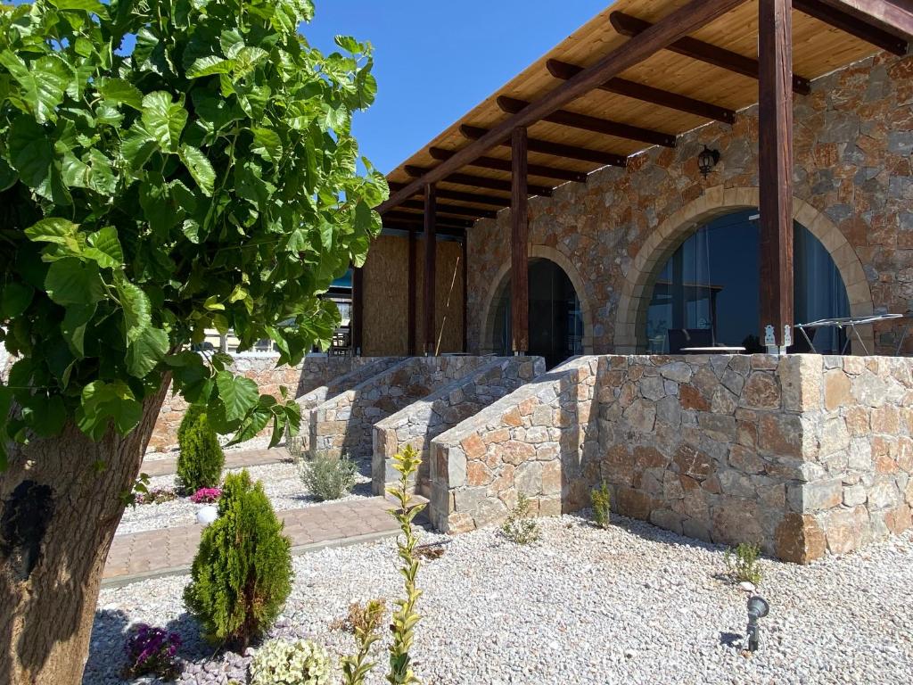 a stone house with a stone wall and a tree at Blue Sky in Frangokastello