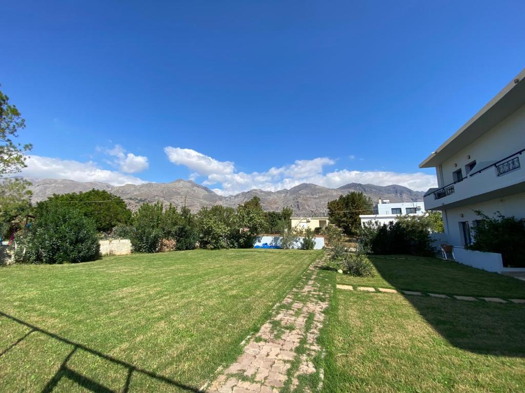 a large yard with a house and mountains in the background at Blue Sky in Frangokastello