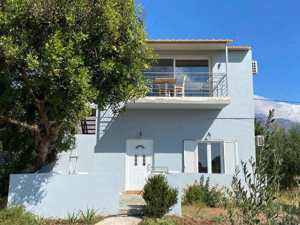 a white house with a balcony and a tree at Blue Sky in Frangokastello