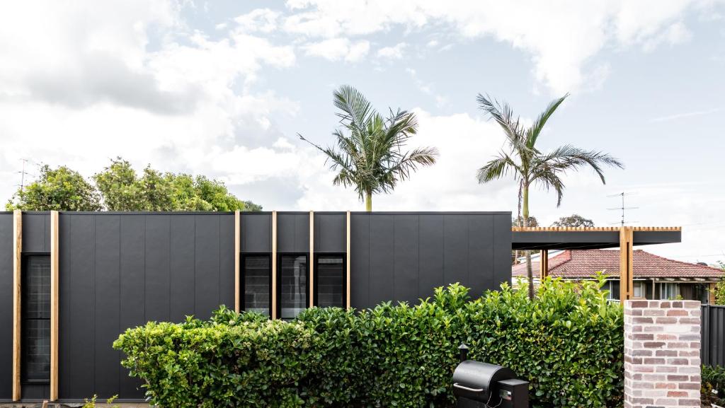 a black house with palm trees in the background at Studio On Park in Albion Park