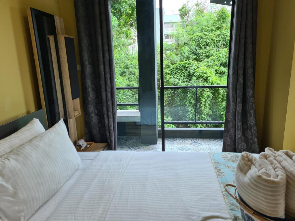 a bedroom with a bed and a large window at The Lantern Suites in Ban Song Hong