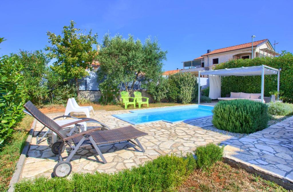 a backyard with a pool and a table and chairs at Holiday house NIKA with pool and jacuzzi in Linardići