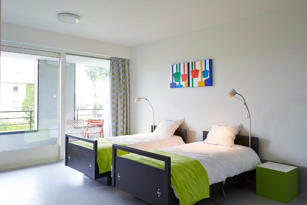 2 Betten in einem Zimmer mit Balkon in der Unterkunft Hotel Middelpunt - Gratis Parking - Ontbijt inbegrepen! in Middelkerke