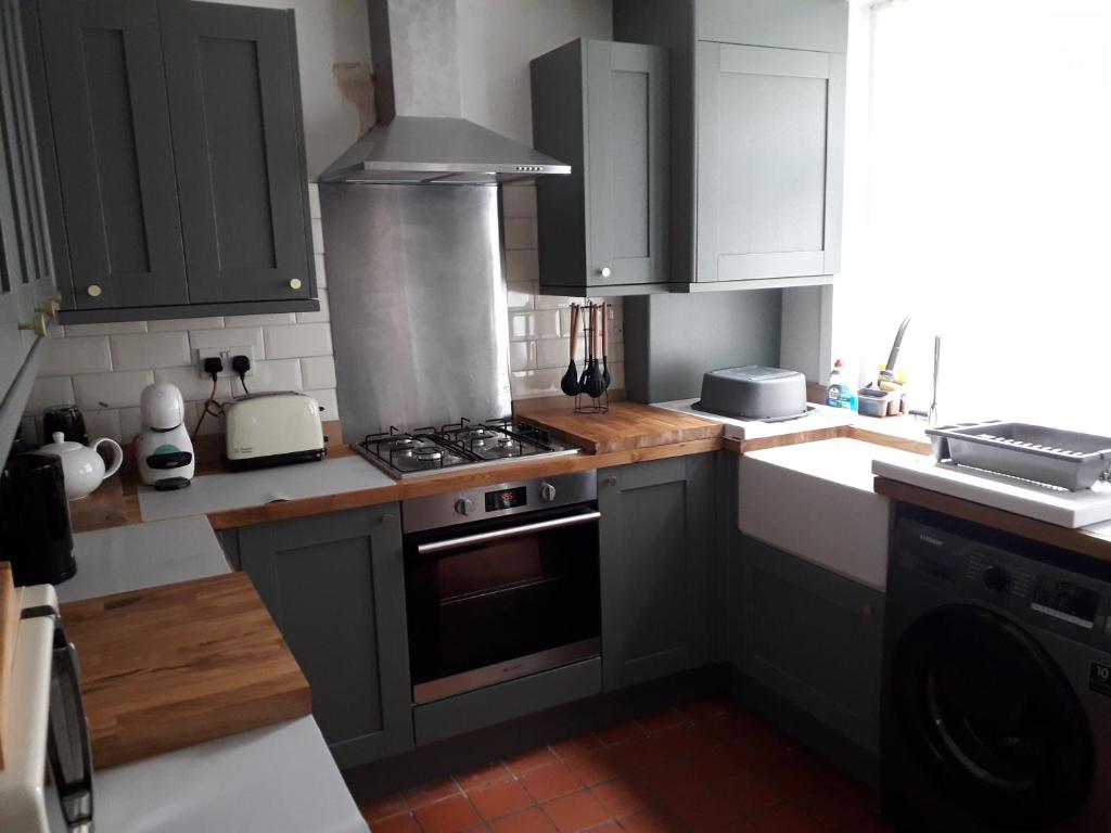 a kitchen with gray cabinets and a stove top oven at Traditional House near Liverpool city centre in Liverpool