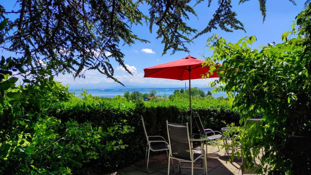 een tafel en stoelen met een rode parasol bij Haus am Trielberg in Meersburg