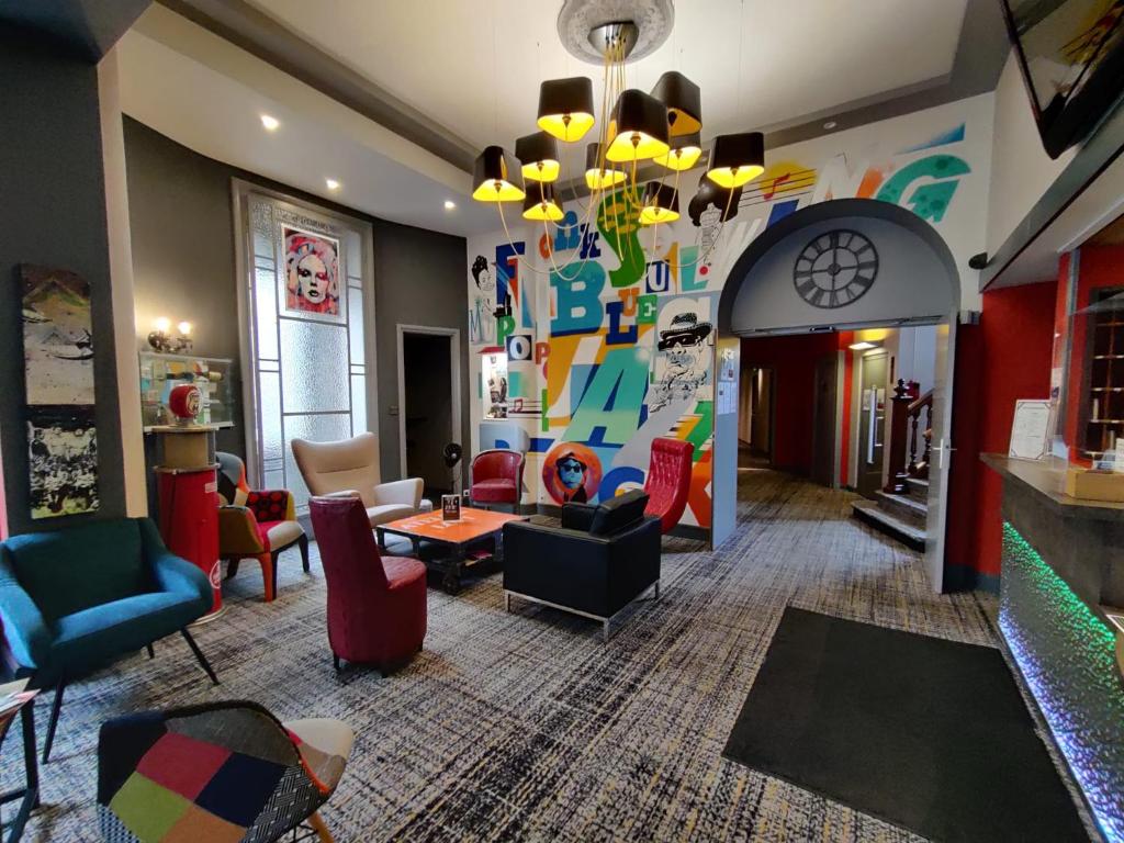 a living room with colorful furniture and a chandelier at The Originals Boutique, Hôtel de l'Univers, Montluçon (Inter-Hotel) in Montluçon