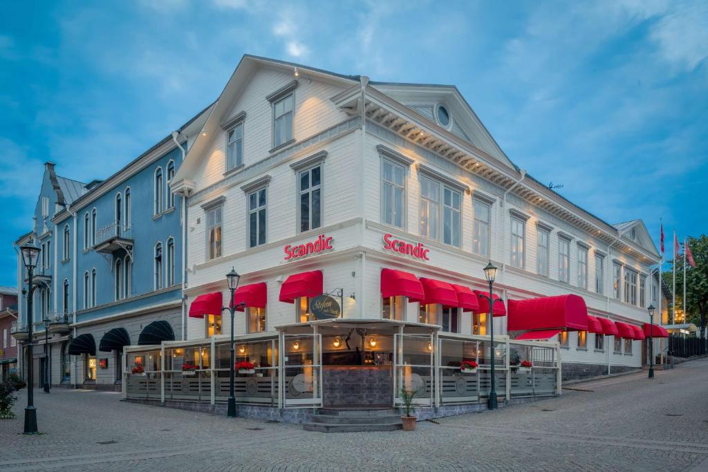 a large white building with red awnings on a street at Scandic Arvika in Arvika