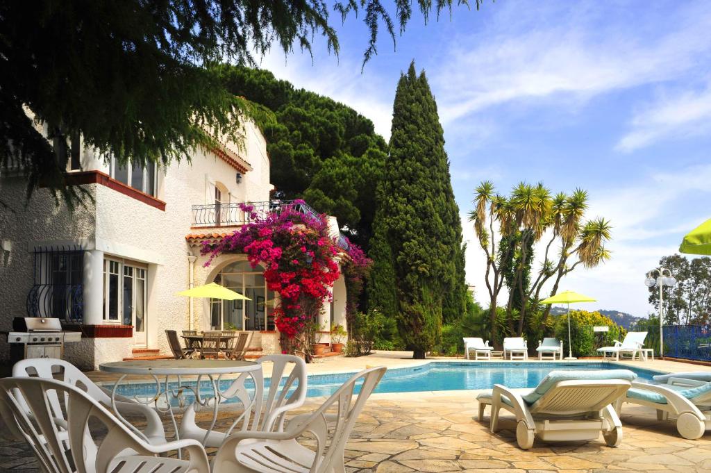 una piscina con sillas, una mesa y una casa en Villa Horizon Bleu, en Cannes