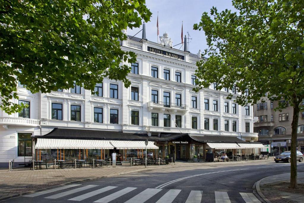 a white building with tables and chairs in front of it at Scandic Kramer in Malmö