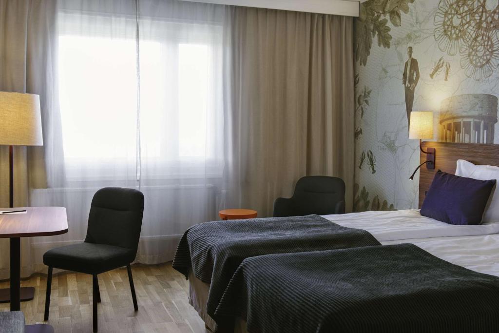 a hotel room with a bed and two chairs and a window at Scandic Kungens Kurva in Stockholm