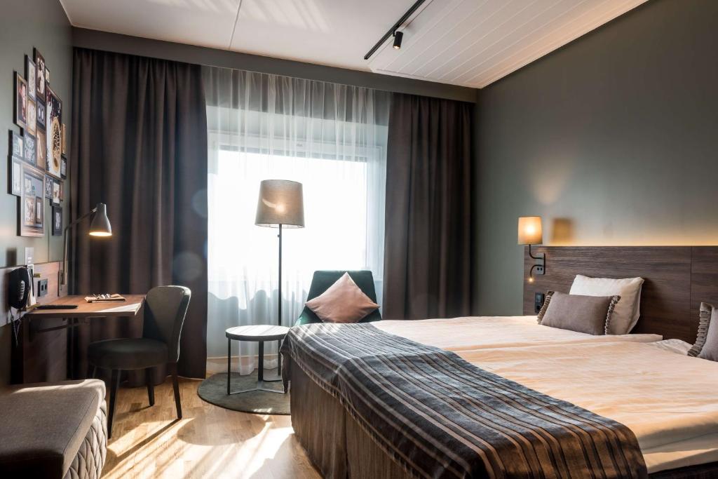 um quarto de hotel com uma cama, uma secretária e uma janela em Scandic Infra City em Upplands-Väsby