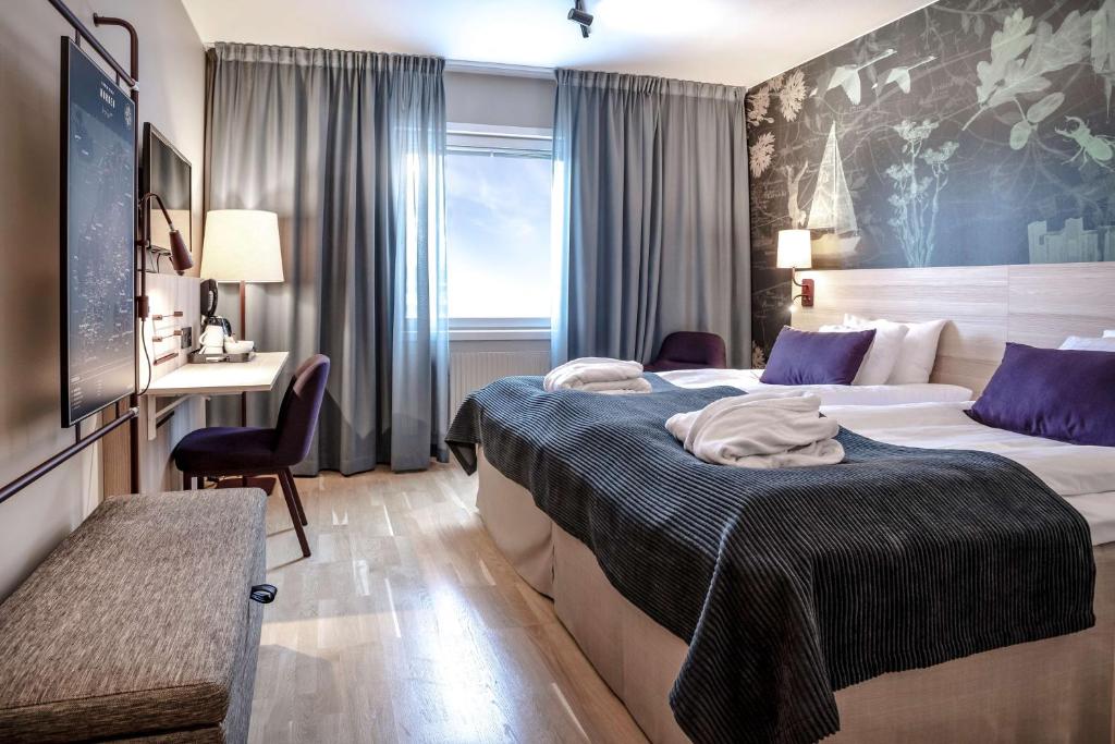 a hotel room with a bed, chair, and nightstand at Scandic Linköping Väst in Linköping