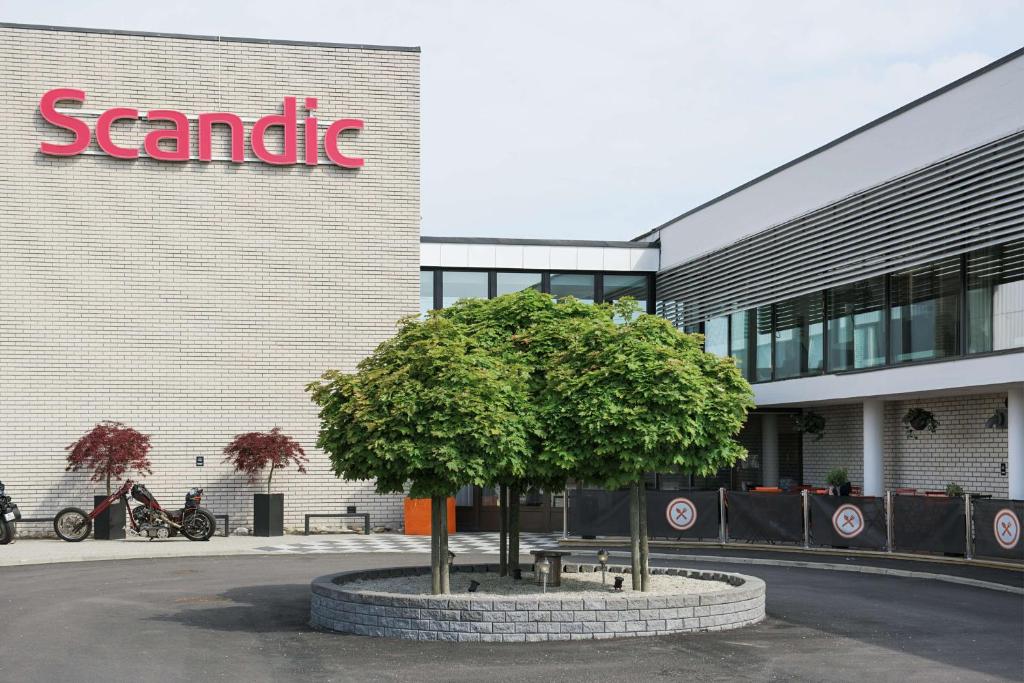 un árbol frente a un edificio con una señal de asale en Scandic Segevång, en Malmö