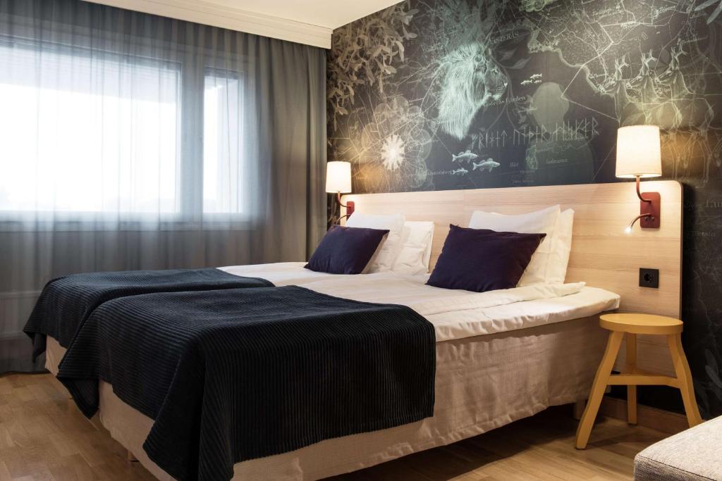 a hotel room with a large bed with blue pillows at Scandic Västerås in Västerås