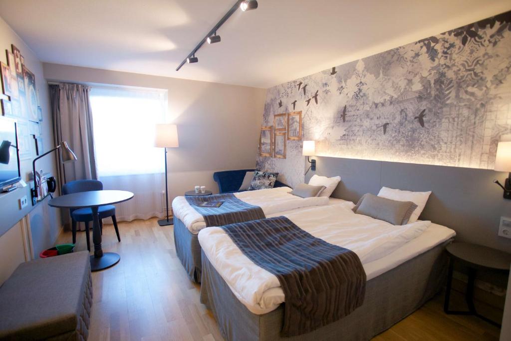 ein Hotelzimmer mit 2 Betten und einem Tisch in der Unterkunft Scandic Winn in Karlstad