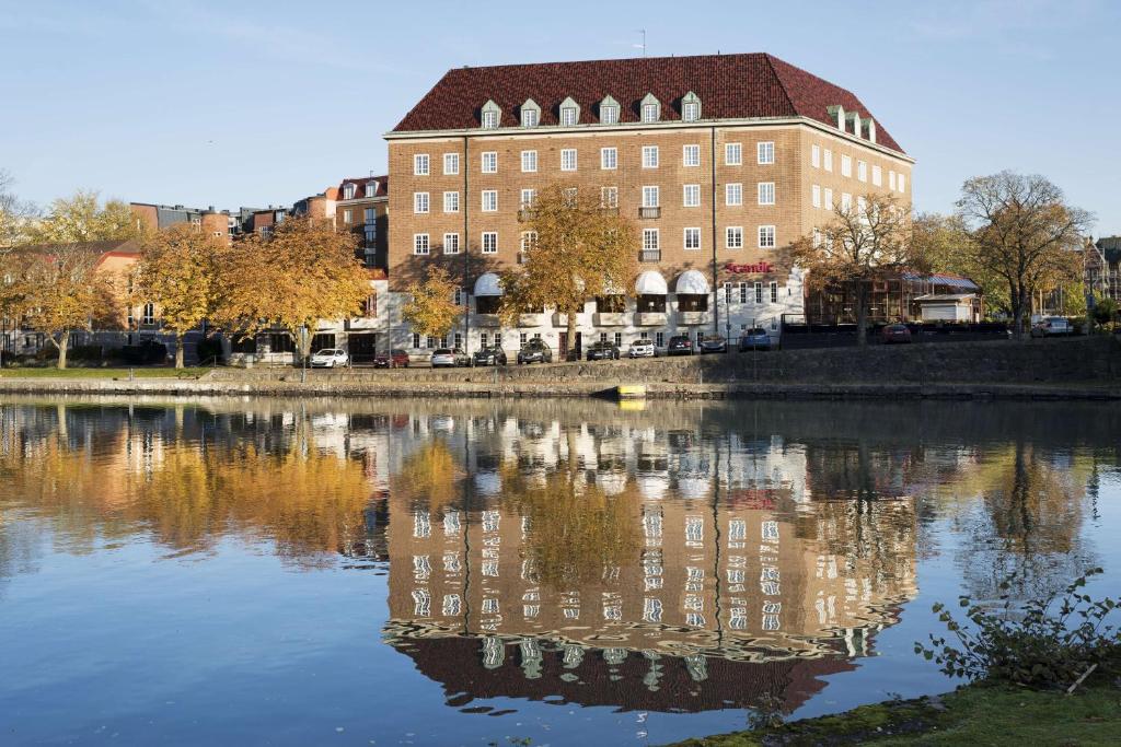 um edifício com o seu reflexo numa massa de água em Scandic Swania em Trollhättan