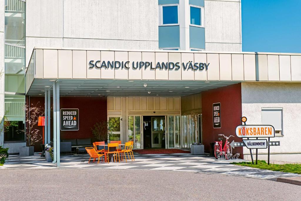 a building with tables and chairs in front of it at Scandic Upplands Väsby in Upplands-Väsby