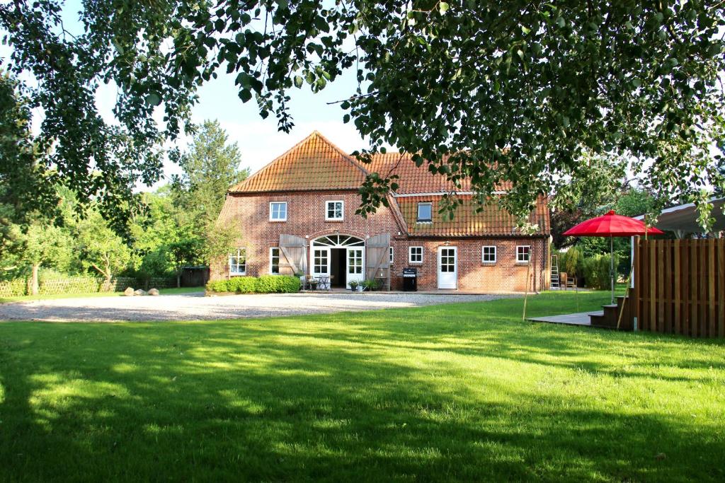 a large brick house with a red umbrella in the yard at Ferienhaus Holy Home in Großenbrode