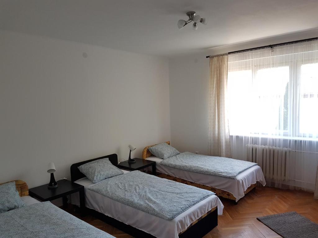 a room with three beds and a window at Kuckó Apartman Berente in Berente