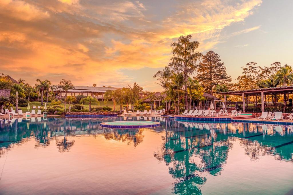 a pool at a resort with a sunset at Vila Ventura Ecoresort in Viamão