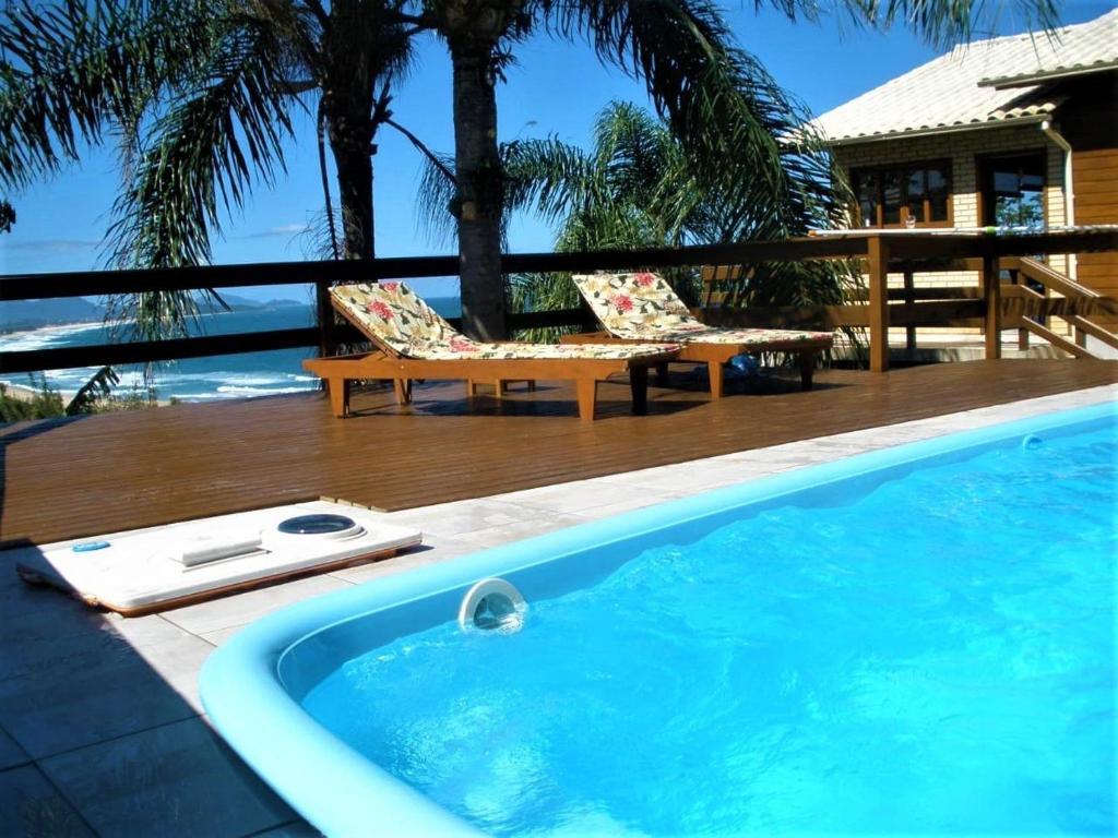 een zwembad met 2 stoelen en een tafel bij Casa Vista Privilegiada: Piscina e Conforto in Garopaba