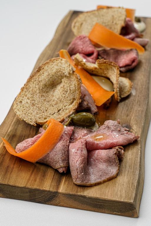 a wooden cutting board with a sandwich and meat and vegetables at Masseria Borgo Santuri in Ostuni