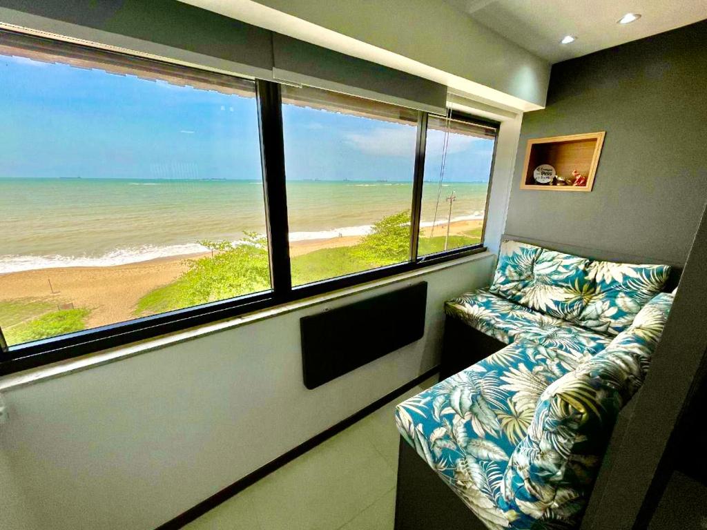 um quarto com um sofá e vista para a praia em INCRIVEL FLAT106 PASSARGADA VISTA p MAR em Vila Velha