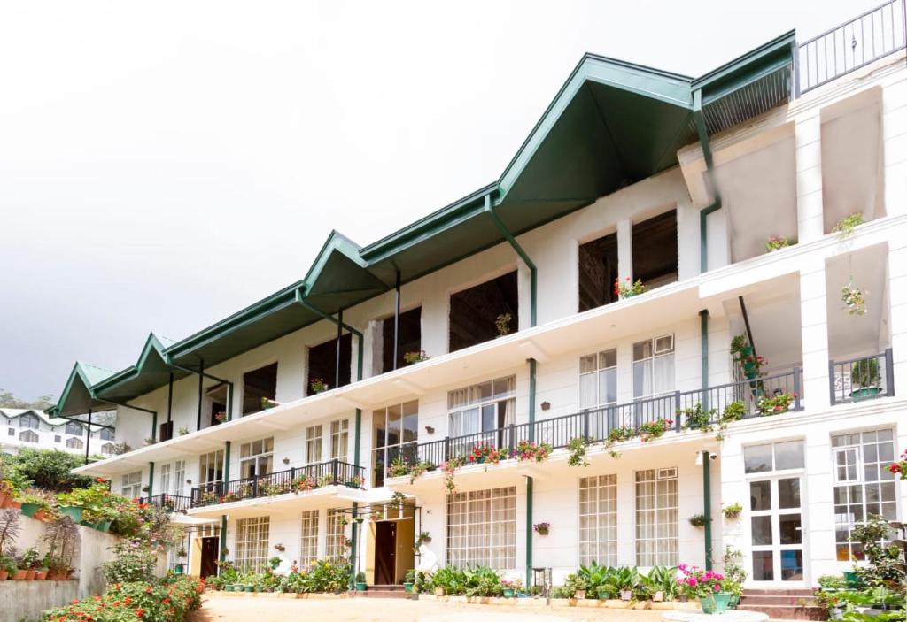 un gran edificio blanco con ventanas y plantas en Ovi Court City Apartments Nuwara Eliya en Nuwara Eliya