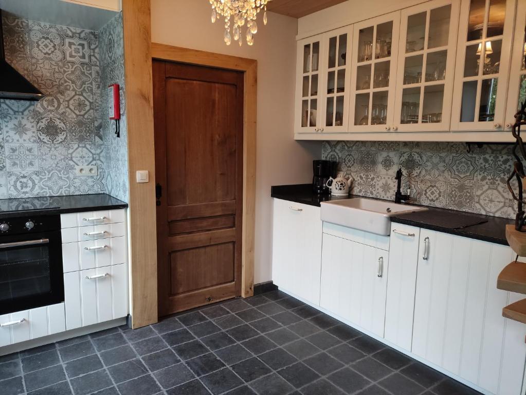 una cucina con armadietti bianchi e porta in legno di Gîte dix-huit a Les Hayons