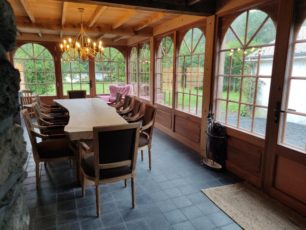a dining room with a table and chairs and windows at Gîte dix-huit in Les Hayons