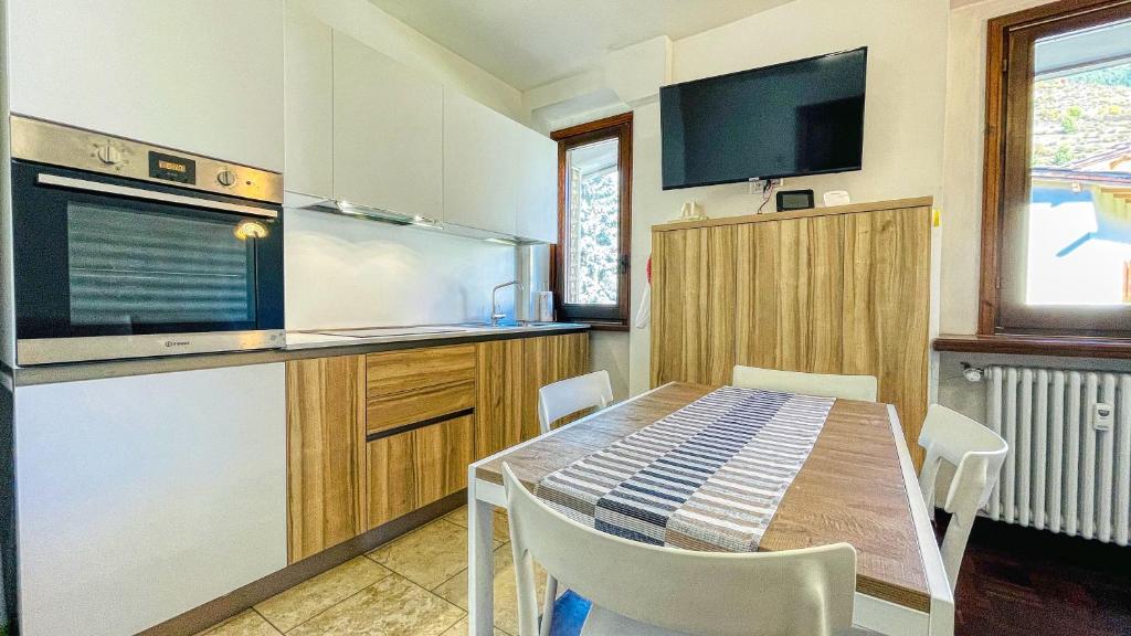 cocina con mesa con sillas y TV en Appartamento Winter Garden - Affitti Brevi Italia, en Bardonecchia
