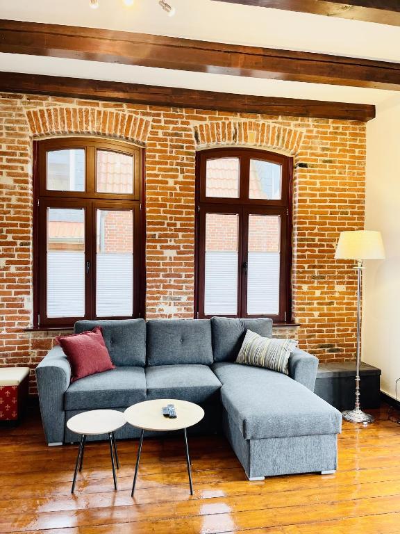 a living room with a blue couch and a brick wall at Charmante Ferienwohnung mit Terrasse im Herzen von Norden in Norden