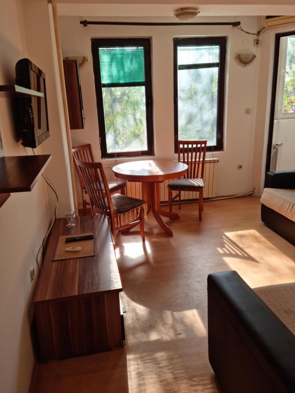 sala de estar con mesa, sillas y ventanas en Lester Apartments, en Skopje