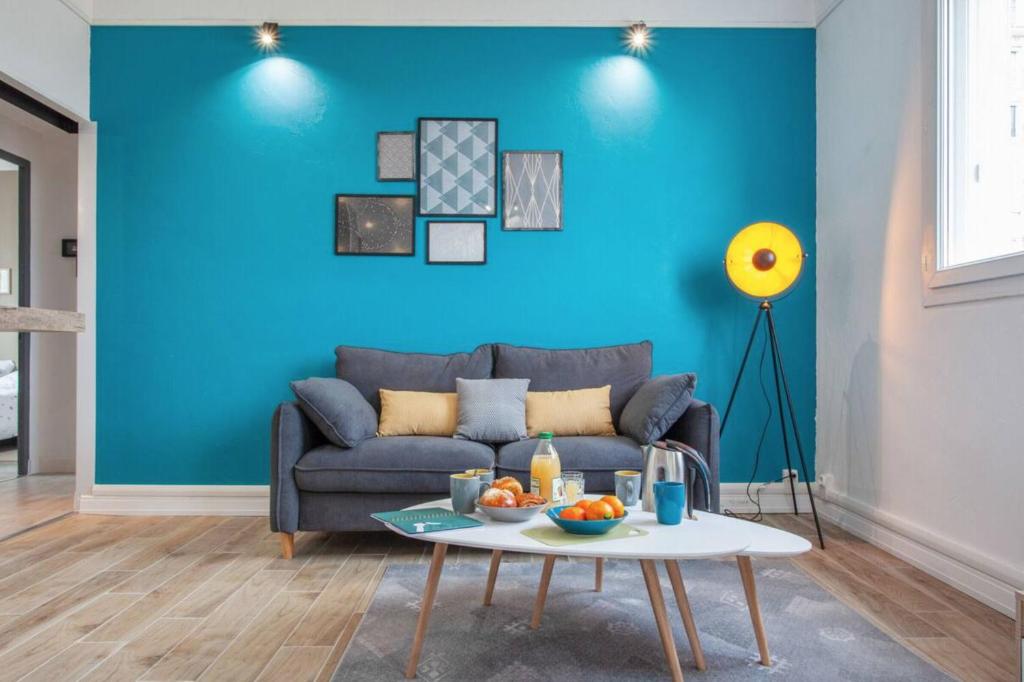 a blue living room with a couch and a table at Atlas - Ovalia in Nîmes