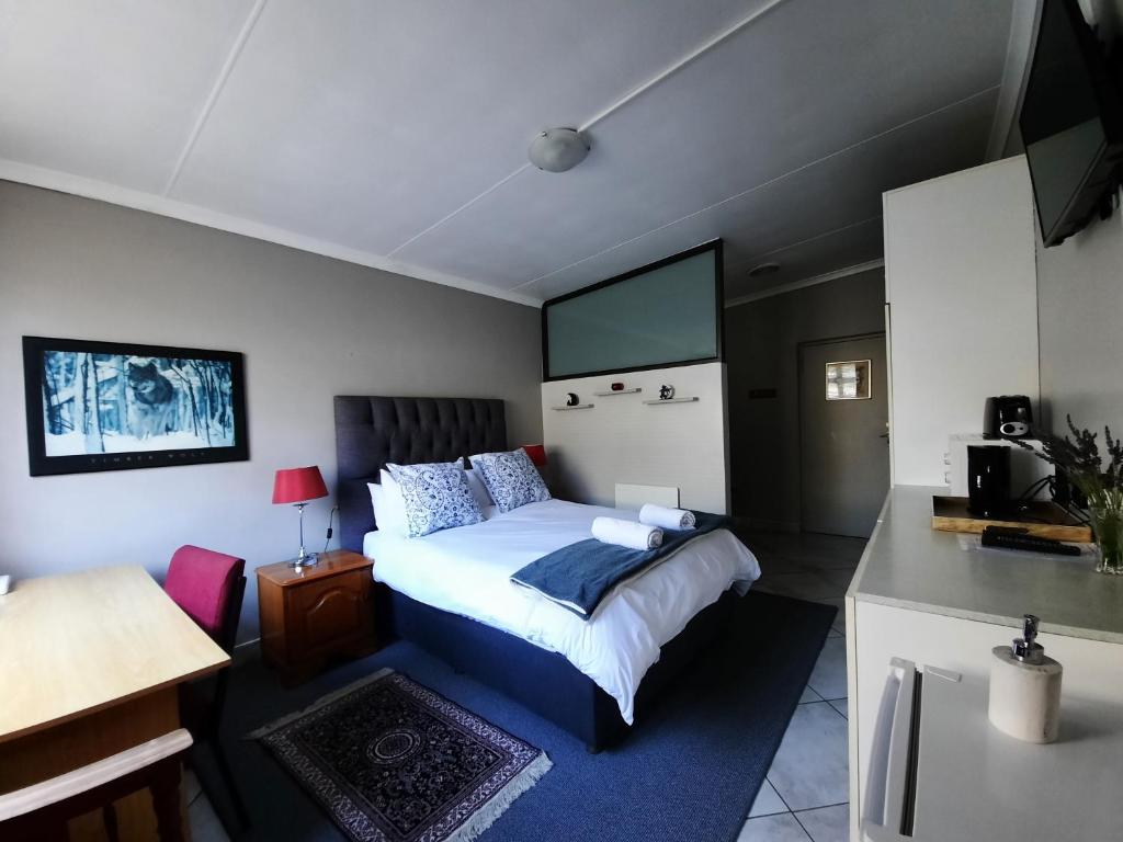 a bedroom with a bed and a desk and a kitchen at Field's Rest in Port Elizabeth