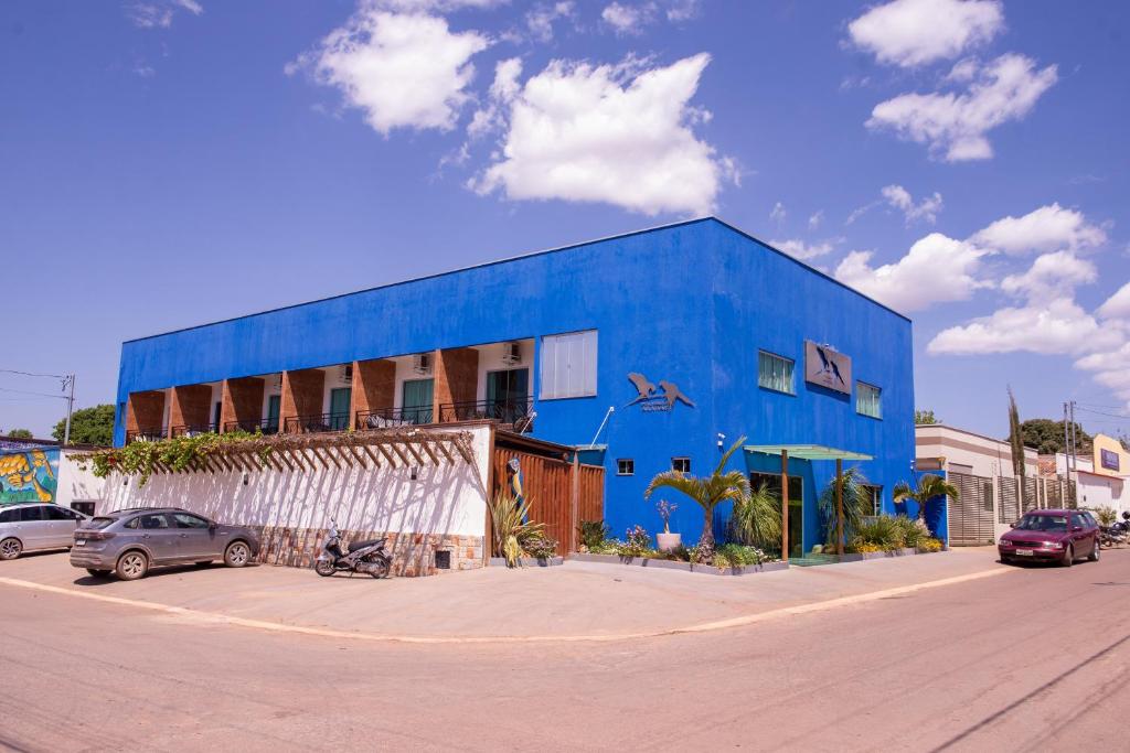 un bâtiment bleu avec des voitures garées devant lui dans l'établissement Pousada Araras, à Alto Paraíso de Goiás