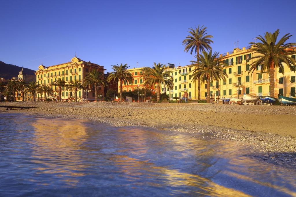a beach with palm trees and buildings in the background at Vicino al mare in Santa Margherita Ligure
