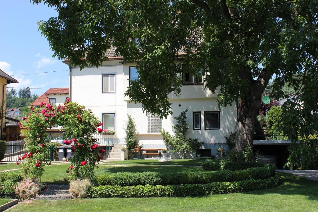 a large white house with flowers in the yard at Ferienwohnung und Gästezimmer Korb in Krumpendorf am Wörthersee