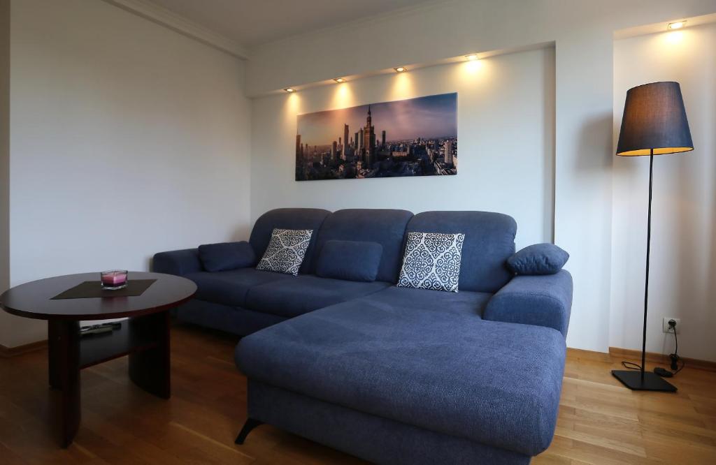 a living room with a blue couch and a table at Apartament MGM Karmelicka in Warsaw