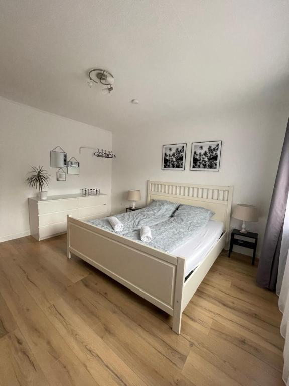 a bedroom with a white bed and a wooden floor at Moderne, helle Wohnung mit Terasse 15min bis OB Centro in Dinslaken