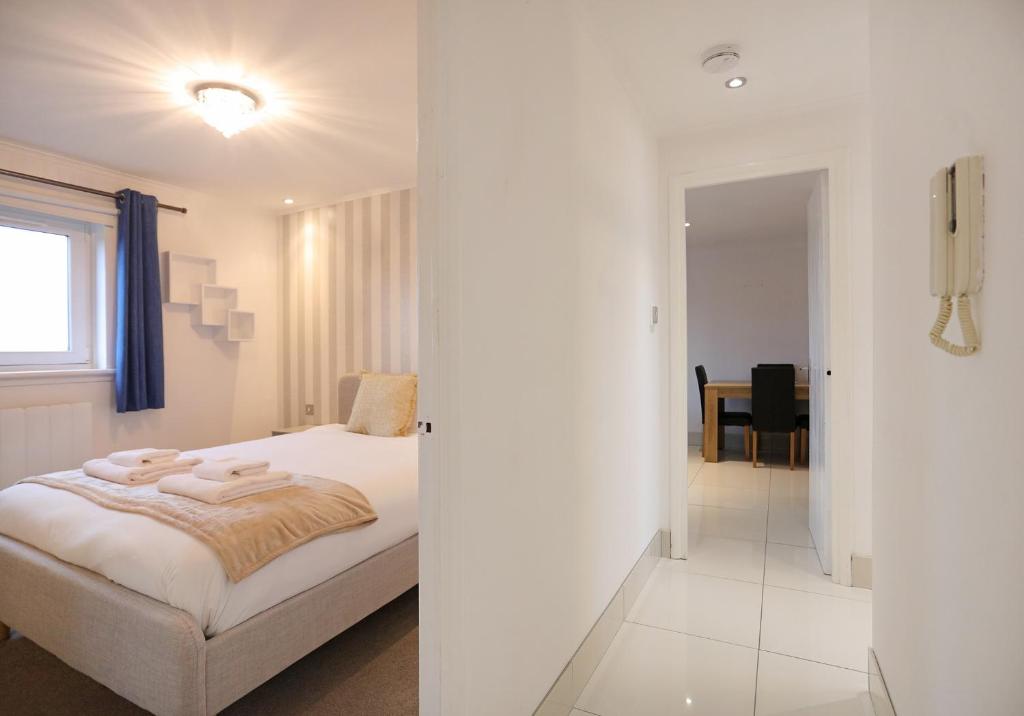 a white bedroom with a bed and a dining room at The South Maybury Residence in Edinburgh