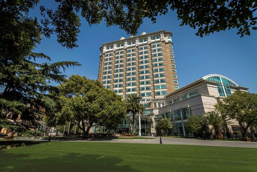 um edifício alto com um parque em frente em Radisson Collection Hotel, Xing Guo Shanghai em Xangai