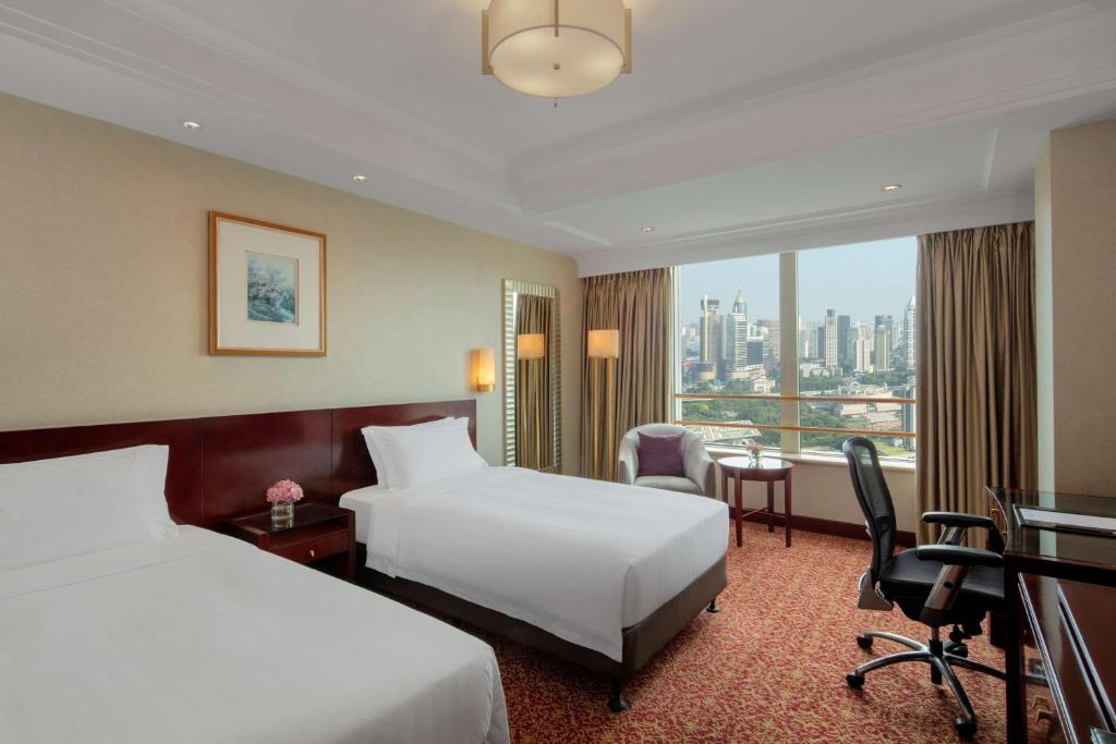 a hotel room with two beds and a desk at Radisson Blu Hotel Shanghai New World in Shanghai