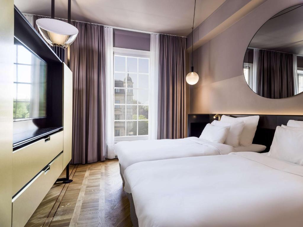a hotel room with two beds and a mirror at Radisson Collection, Strand Hotel, Stockholm in Stockholm