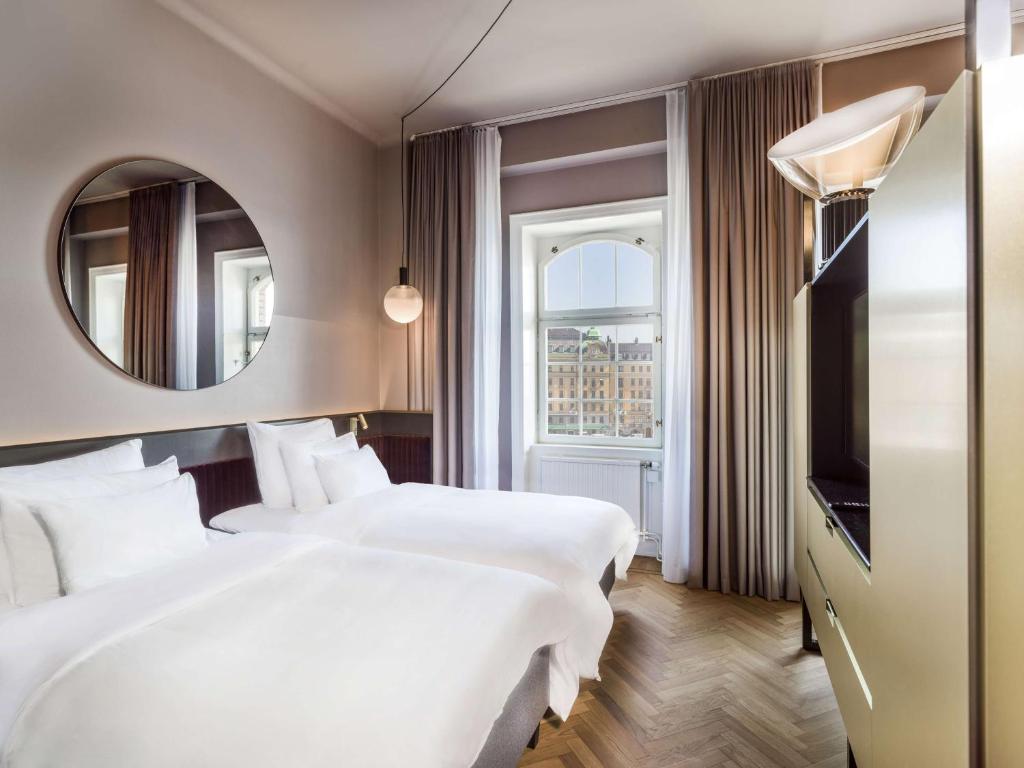 a hotel room with two beds and a mirror at Radisson Collection, Strand Hotel, Stockholm in Stockholm