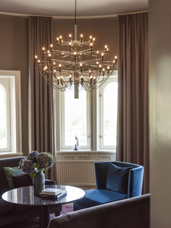 a dining room with a chandelier and a table and chairs at Radisson Collection, Strand Hotel, Stockholm in Stockholm