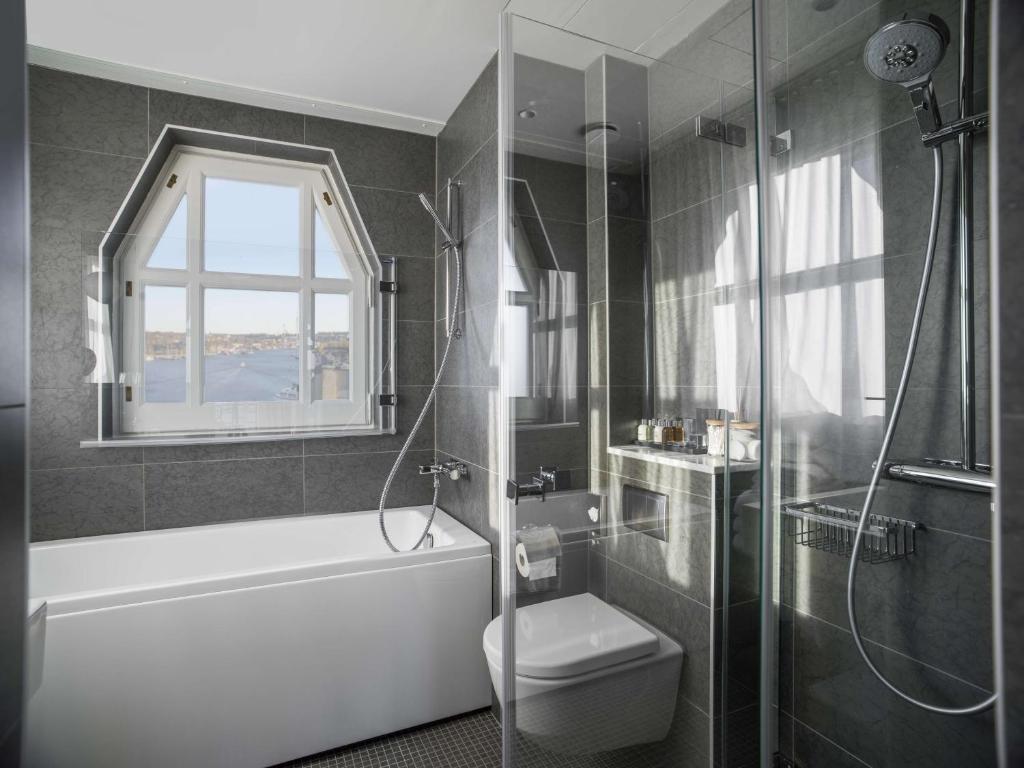 a bathroom with a tub and a toilet and a shower at Radisson Collection, Strand Hotel, Stockholm in Stockholm
