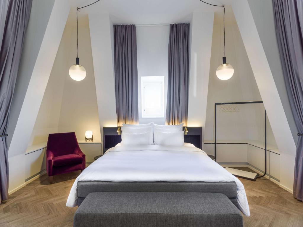 a bedroom with a large bed and a red chair at Radisson Collection, Strand Hotel, Stockholm in Stockholm