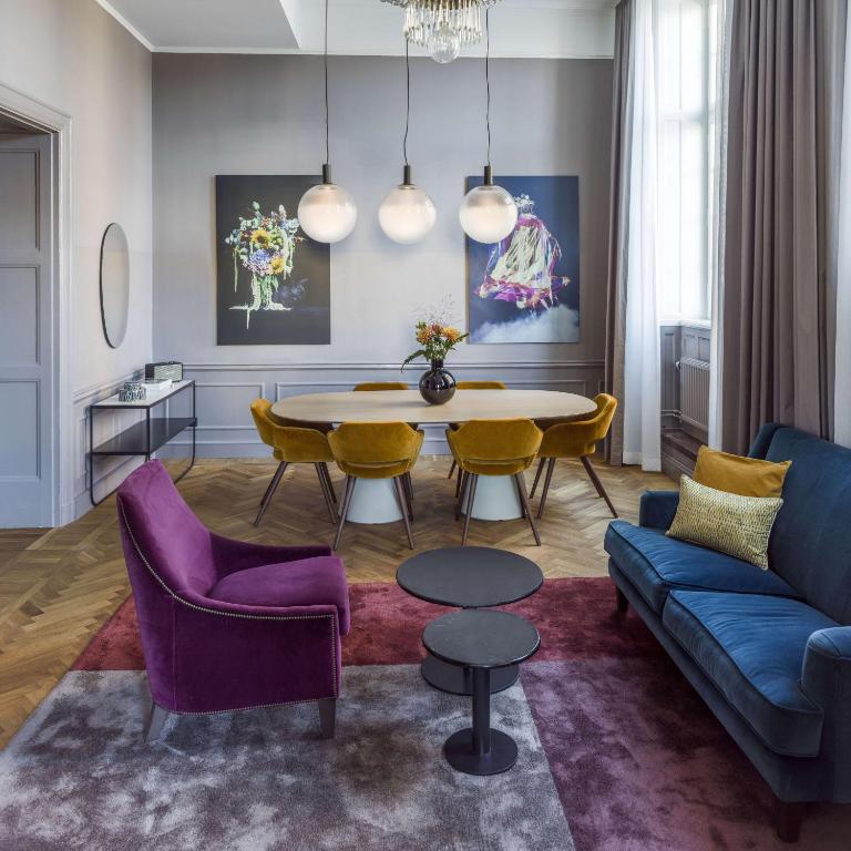 a living room with a table and purple chairs at Radisson Collection, Strand Hotel, Stockholm in Stockholm
